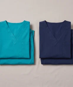 Two complete LumiScrubs scrub sets in teal and navy, folded — the $99 Team Sample Kit