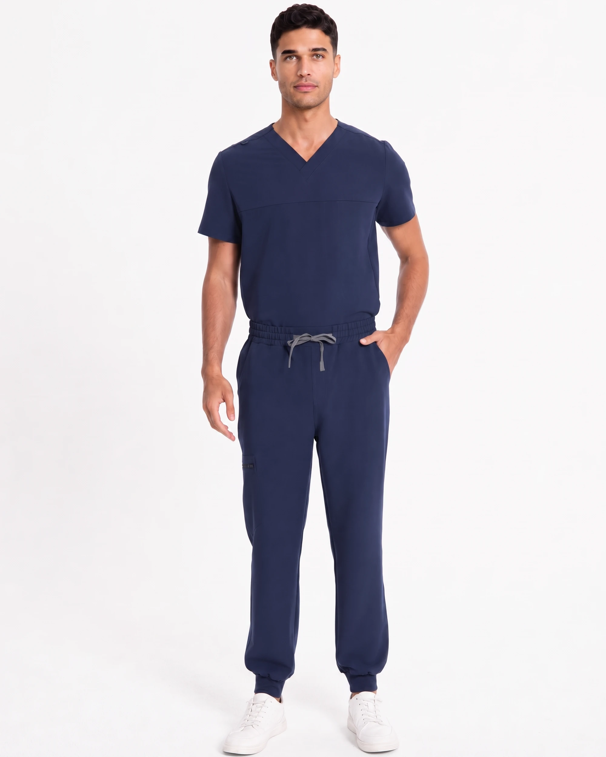 Navy men's Motion scrub set shown from the front with a V-neck top, drawcord waistband, tapered jogger pants, cuffs, and white shoes