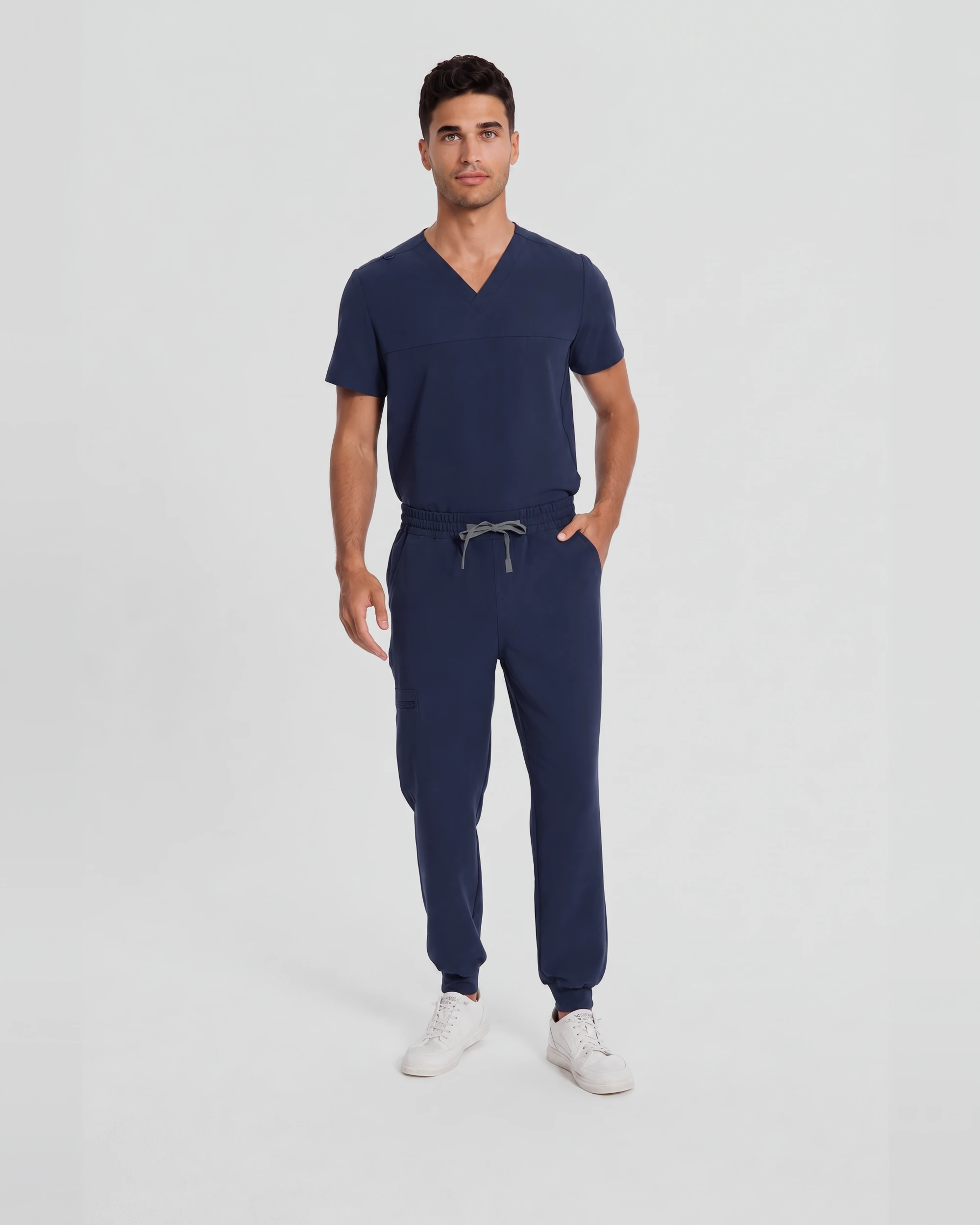 Man wearing the Motion Scrub Set in Navy, front three-quarter view showing the V-neck top, drawcord waistband, and cuffed jogger pant