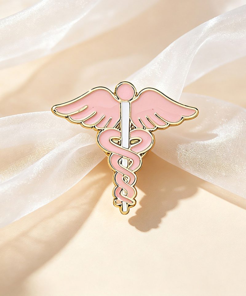 Pink winged caduceus enamel pin with a gold outline