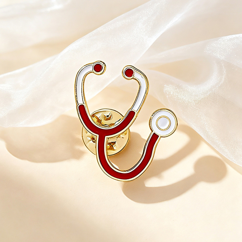 Red and white stethoscope enamel pin with a gold outline